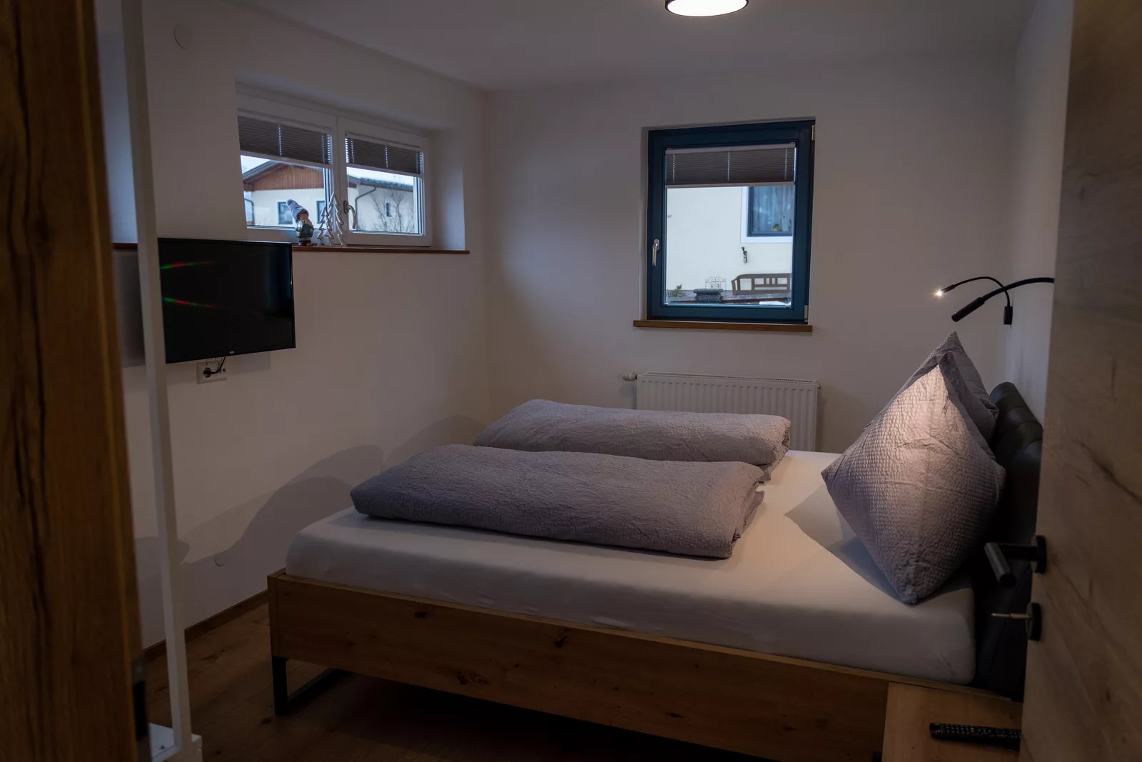 Gemütliches Schlafzimmer mit Holzbett und Wandmontiertem TV